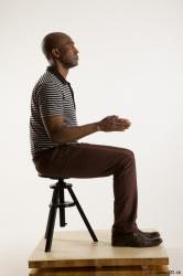 Sitting reference of whole body black white striped shirt brown jeans brown shoes Arturo